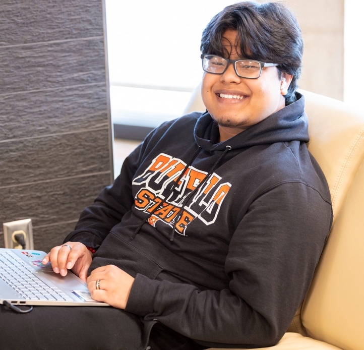 Smiling student in the lounge with a laptop